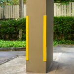 Closeup corner guard or column protector attached to concrete column in parking lot. This can reduce damages caused by car impact
