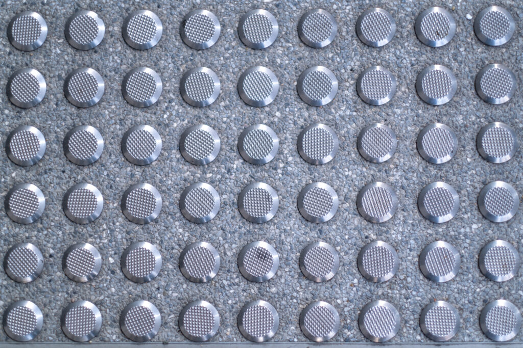 Closeup of iron non-slip curb ramp treads sidewalk texture