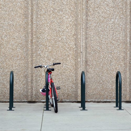 Red bike in rack in front of concrete wall